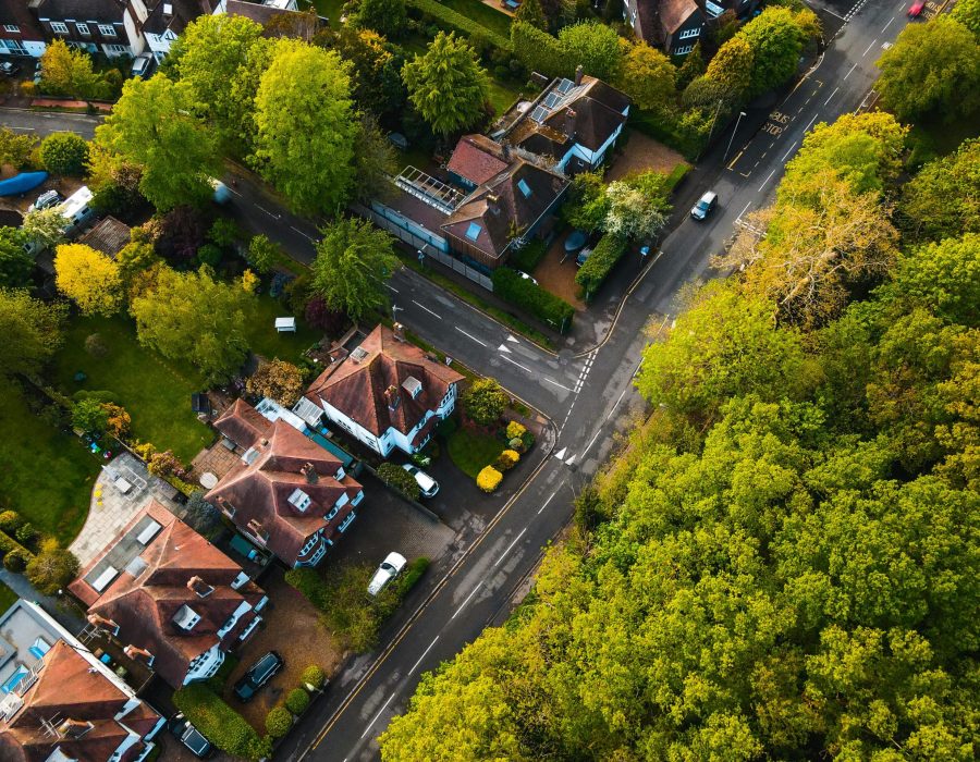 Aerial view of an English suburban neighborhood with green spaces and roads.